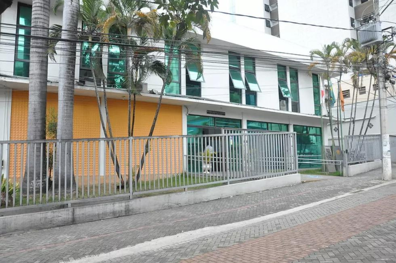 Fachada da Escola do Legislativo em Divinópolis, destacando as janelas verdes e detalhes em laranja.