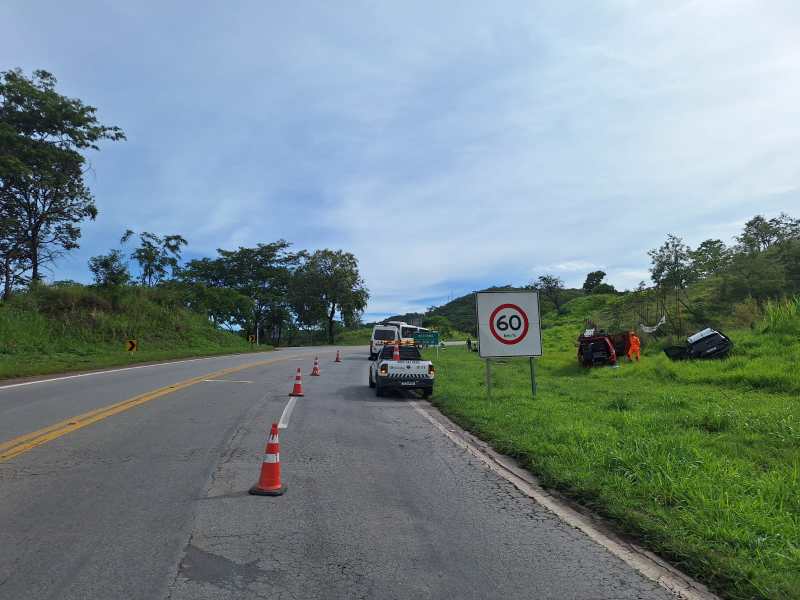 Scene of a road on a hill with traffic cones and a speed limit sign of 60. A rescue vehicle is parked nearby, and there is a car overturned in the grass.