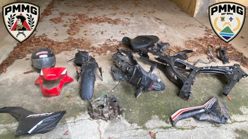Peças de motocicleta coletadas em operação da Polícia Militar, incluindo chassi, motor e acessórios, dispostas em uma superfície com folhas secas ao redor.