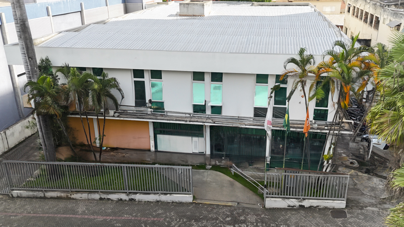 Vista externa da Câmara Municipal de Divinópolis, destacando a fachada do prédio com bandeiras e área ajardinada.