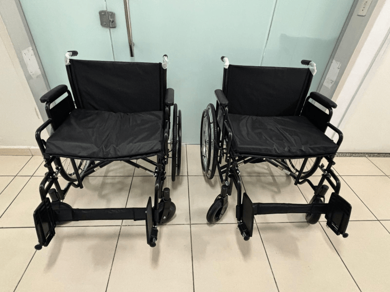 Duas cadeiras de rodas pretas em um ambiente interno, representando equipamentos doados para a Unidade de Pronto Atendimento.