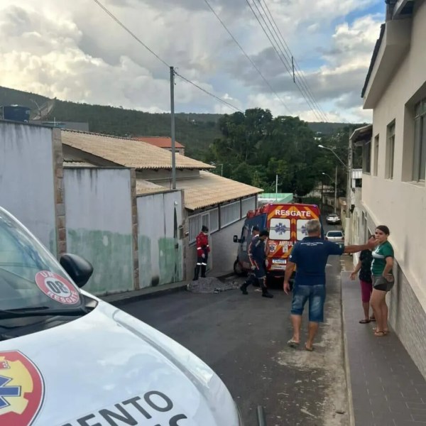 Ambulância do resgate em uma rua residencial, com pessoas observando a cena.