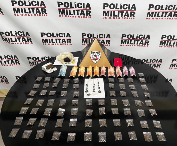Mesa com várias embalagens de drogas apreendidas pela Polícia Militar de Minas Gerais, incluindo pacotes coloridos e itens variados dispostos uniformemente.