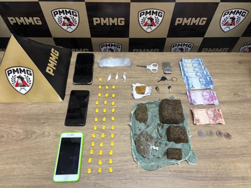 Mesa com objetos confiscados incluindo celulares, dinheiro, drogas e materiais de uso em tráfico.