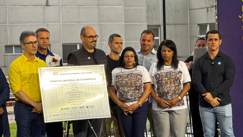 Cerimônia de inauguração do Hospital Regional de Divinópolis, com várias pessoas sorrindo e segurando uma placa comemorativa.