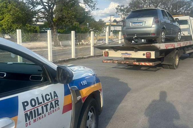 Viatura da Polícia Militar de Minas Gerais com um carro sendo rebocado por um caminhão guincho.