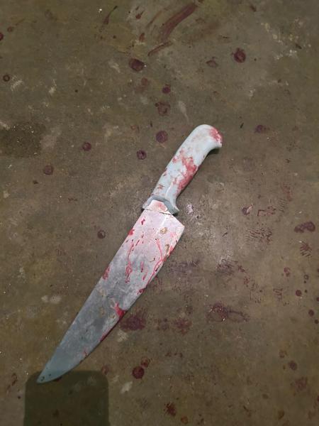 Uma faca com manchas de sangue, descansando sobre um piso sujo.