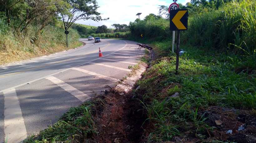 Estrada curvada com sinalização de 60km/h e cone de aviso, próximo a uma vala ao lado da pista.