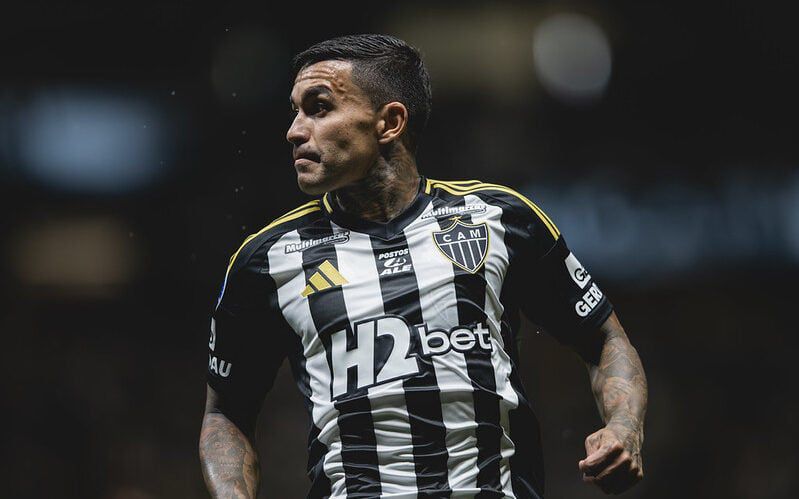 A football player in a black and white striped jersey, celebrating during a match.
