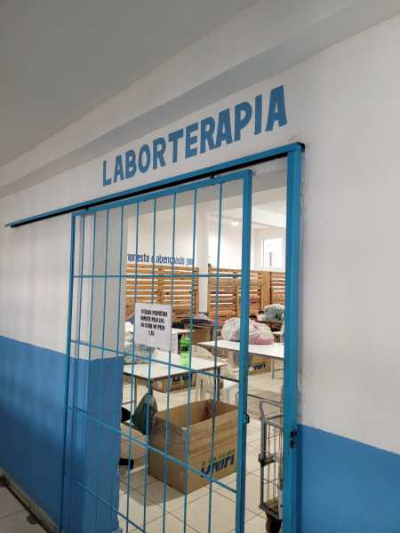 Entrada de um espaço chamado 'Laboroterapia' com uma parede azul e uma grade na porta.