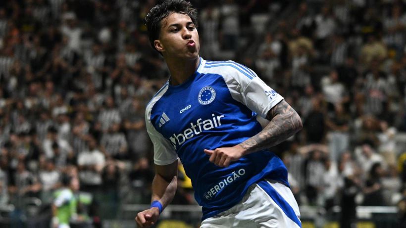 A football player celebrating a goal, wearing a blue and white soccer uniform with the logo 'betfair'. The background features a cheering crowd in a stadium.