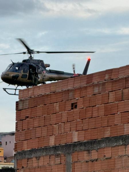 Helicóptero sobrevoando um muro de tijolos em um cenário urbano.