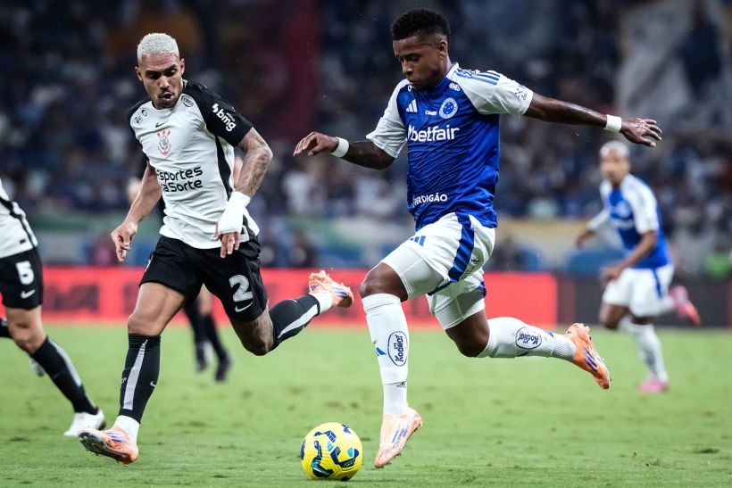A competitive soccer match featuring two players in action, with one wearing a black and white uniform and the other in a blue kit, both focused on the ball on the field.
