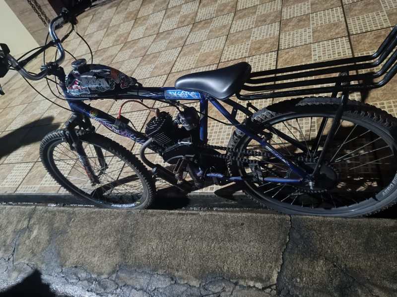 Bicicleta motorizada estacionada em uma calçada, com desenhos coloridos e um motor visível.
