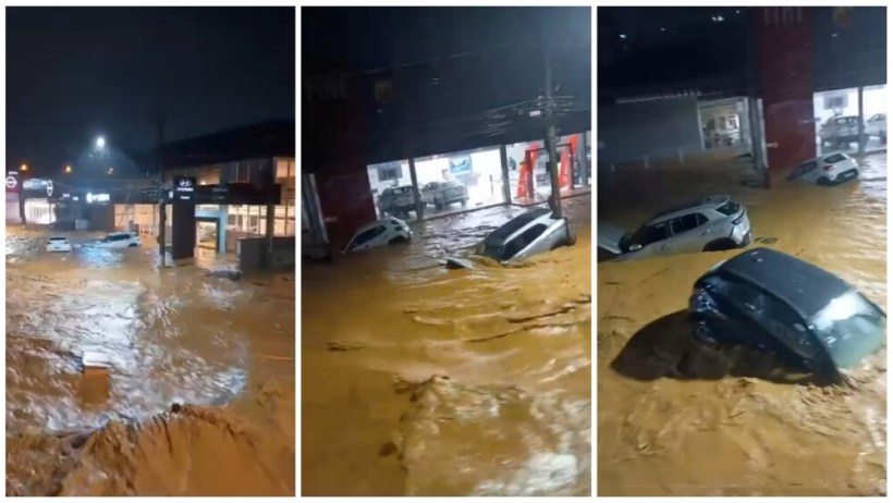 Inundação em área urbana com carros submersos em água marrom durante a noite.