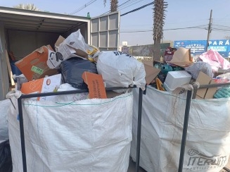 Dois contêineres brancos cheios de lixo e materiais recicláveis, com caixas e sacos visíveis.