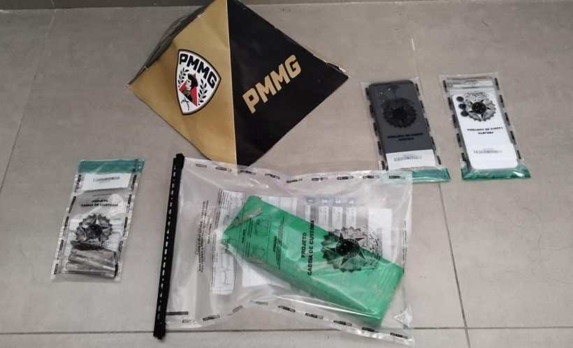 Materiais de segurança policial dispostos em uma superfície, incluindo embalagem e itens identificáveis da PMMG.