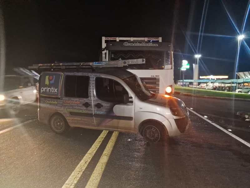 Um veículo de empresa Printix parado em uma estrada à noite, bloqueando uma das faixas enquanto um caminhão e outros carros passam ao fundo.