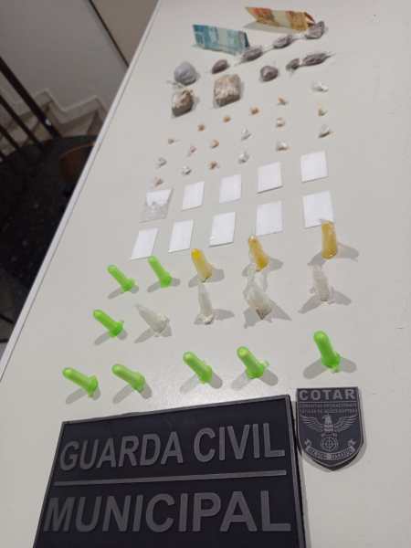 Material apreendido pela Guarda Civil Municipal, incluindo drogas e objetos diversos dispostos em uma mesa.