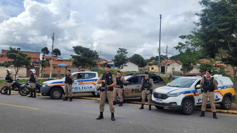 Grupo de policiais em uma operação, com viaturas e equipamentos de segurança em uma rua residencial.