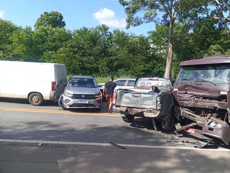 Acidente de trânsito envolvendo um caminhão e vários veículos em uma estrada, com um homem em pé analisando a situação.