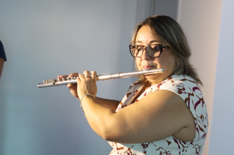 Mulher tocando flauta em um ambiente interno iluminado.
