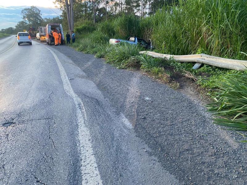 Acidente de carro à beira da estrada, com equipe de resgate e um veículo acidentado em meio à vegetação.