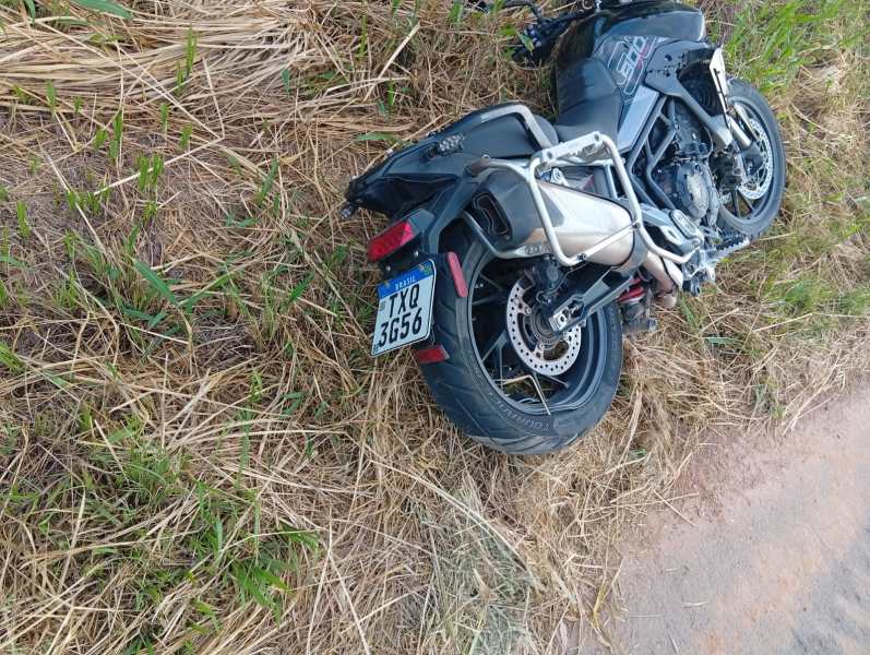 Moto caída em um campo com vegetação rasteira.