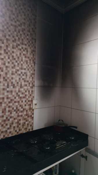 Cozinha com marcas de queimadura na parede e fogão visível.