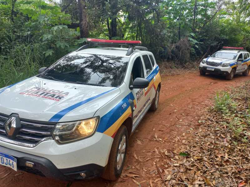 Duas viaturas da polícia em uma estrada de terra cercada por vegetação.