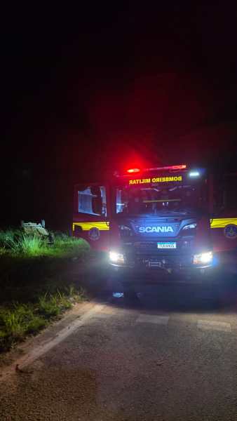 Caminhão de bombeiros Scania com luzes de emergência acesas em uma estrada à noite.