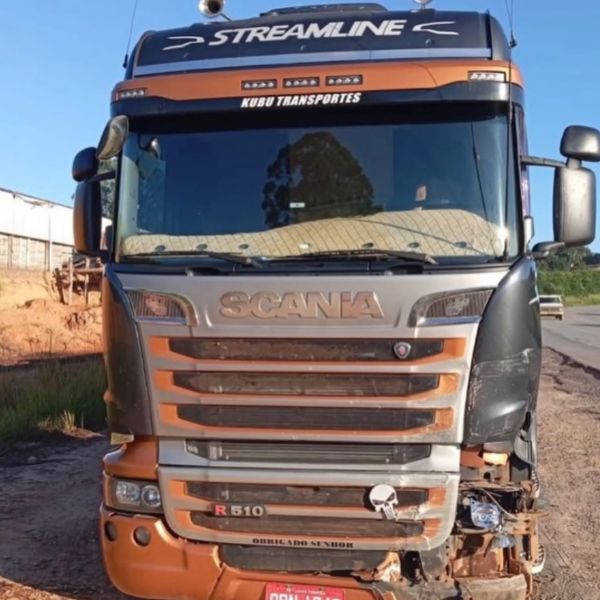 Trator Scania R 510 da empresa Kubu Transportes estacionado na estrada, com detalhes em preto e laranja.