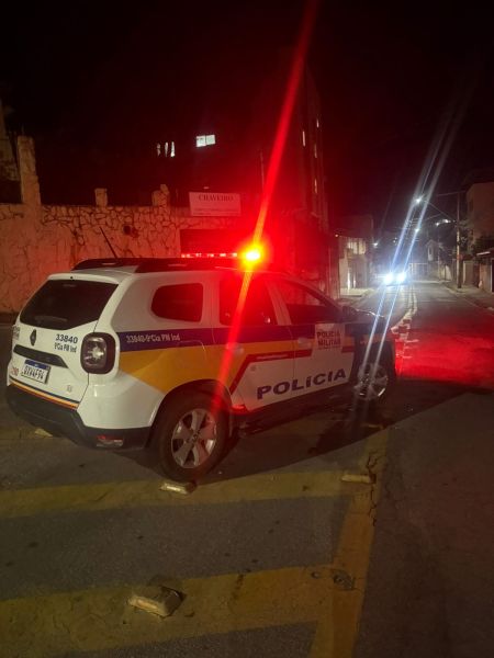 Viatura da polícia parada em uma rua à noite, com luzes de emergência acionadas.