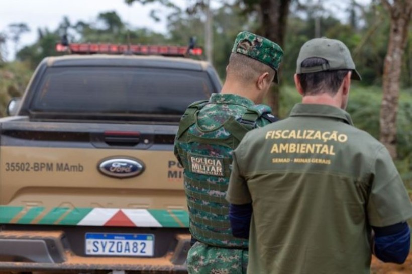 Dois agentes, um da Polícia Militar e outro da fiscalização ambiental, observando uma caminhonete estacionada em meio à vegetação.