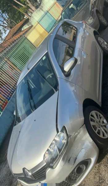 Carro prata estacionado em área com cercas coloridas ao fundo.