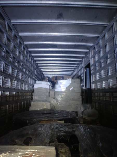 Interior de um caminhão de carga com pilhas de pacotes envolvidos em plástico.