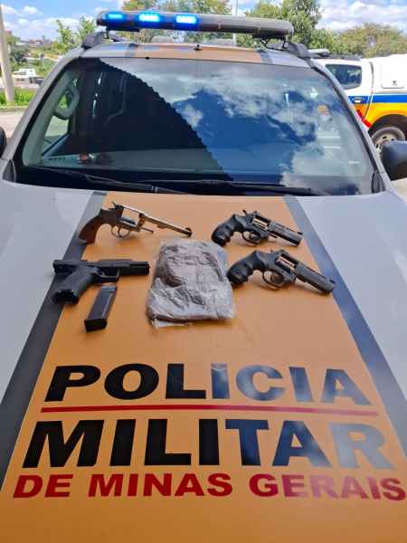 Armas de fogo e entorpecente confiscados sobre o capô de um veículo da Polícia Militar de Minas Gerais.