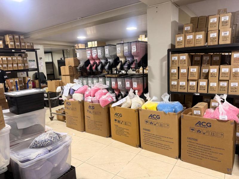 Armazém com caixas de produtos e sacos coloridos de materiais em um ambiente de trabalho.