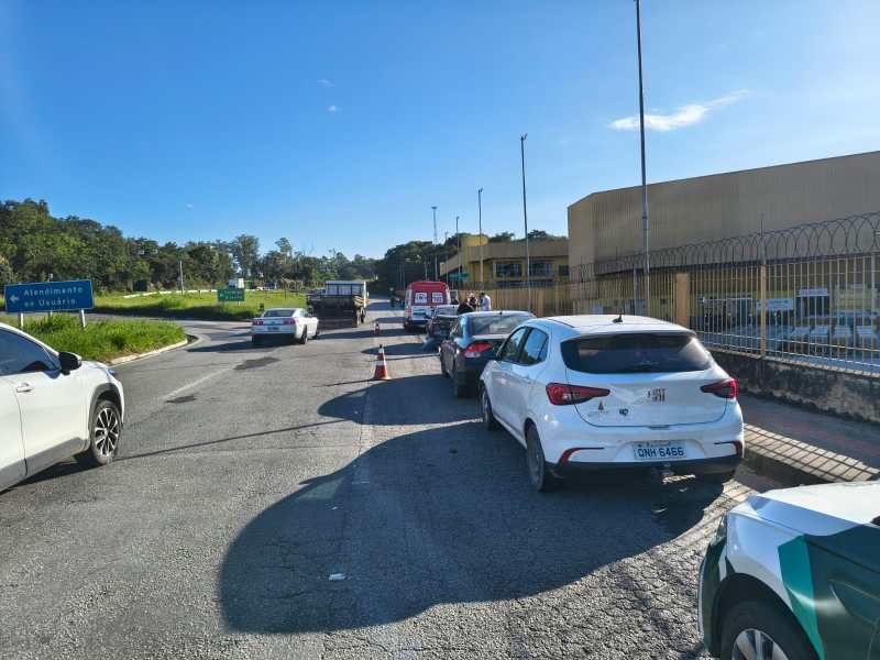 Trânsito em rotatória com vários carros, incluindo veículos brancos, e uma construção à direita.