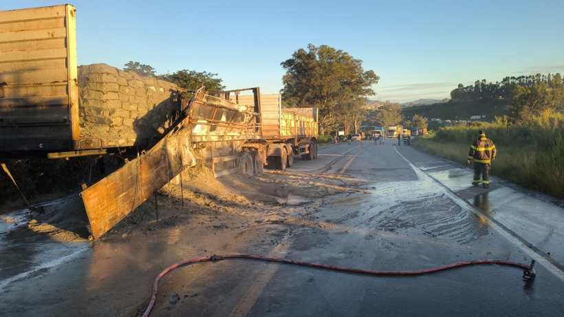 Caminhões envolvidos em um acidente na estrada, com carga de areia espalhada e equipe de resgate no local.