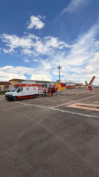 Ambulância e helicóptero de resgate em um aeroporto, com equipe de emergência se preparando para uma missão.