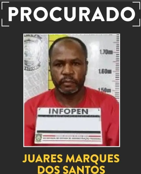 Imagem de um homem de camiseta vermelha, identificado como 'Juares Marques dos Santos', posando para uma foto policial com um cartaz de identificação, ao lado da medida de altura, com a palavra 'PROCURADO' acima.