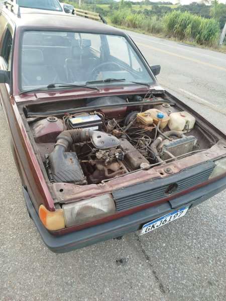 Vista de um carro com o capô aberto, mostrando o motor e componentes internos expostos.