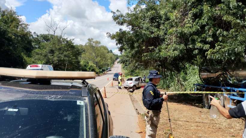 Cenas de uma estrada com agentes da lei em ação, bloqueio de acesso e veículos próximos, cercados por vegetação e céu claro.