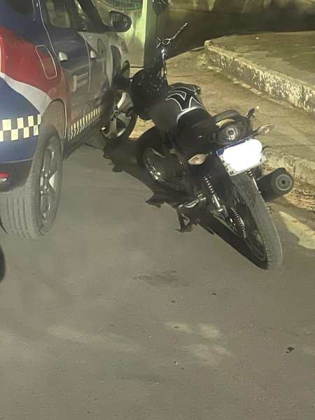 Uma moto preta encostada em um carro de polícia em uma rua.