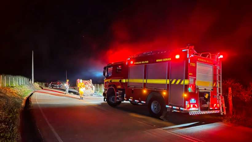 Caminhão do Corpo de Bombeiros estacionado à noite com luzes vermelhas piscando em estrada rural.