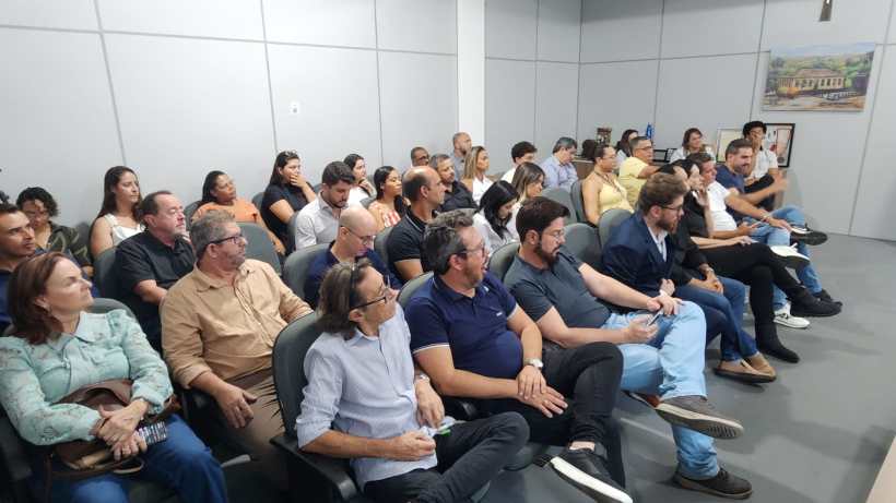 Um grupo de pessoas sentadas em um auditório, assistindo a uma apresentação.