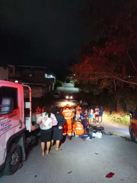 Equipe de emergência em atendimento a um incidente em uma rua à noite, com pessoas assistindo ao ocorrido.