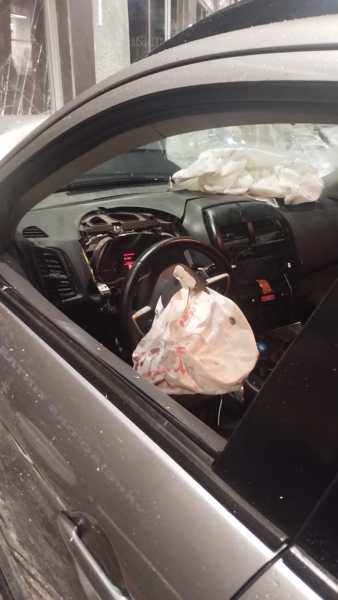 Interior de um carro com o airbag acionado e sacola pendurada no volante.
