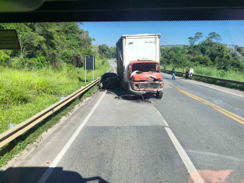 Acidente de trânsito envolvendo um caminhão vermelho ao lado da estrada, com danos visíveis, e pessoas na cena.